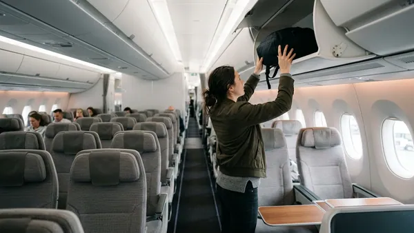 Passenger stowing cabin backpack in overhead bin on Air France flight