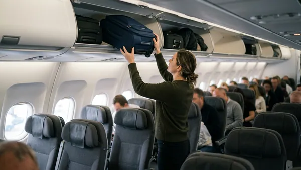 Passenger placing cabin bag into aircraft overhead locker on easyJet flight