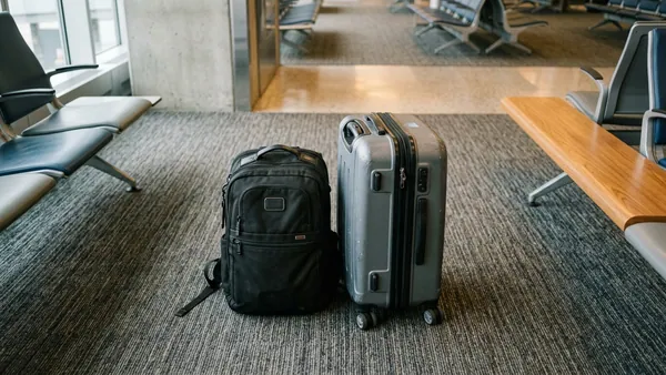 Personal item backpack and larger cabin bag side by side on airport terminal floor