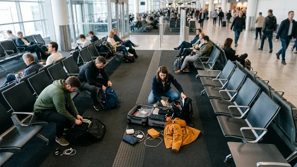 Passengers preparing cabin bags at airport gate before boarding budget airline flight