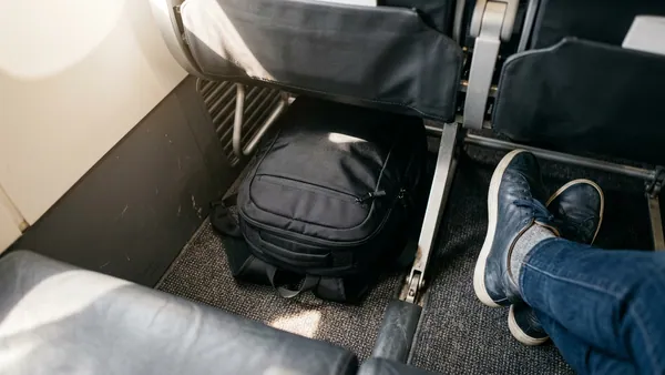 Underseat cabin bag fitting neatly under airline seat on Ryanair flight, showing maximum free hand luggage allowance