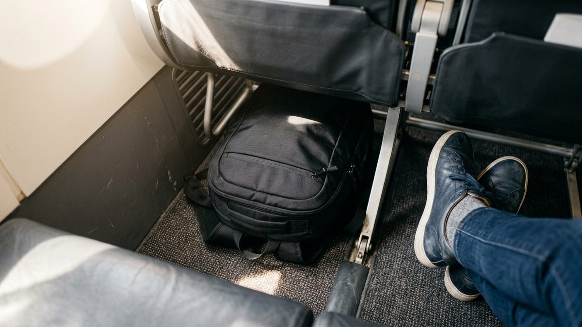 Underseat cabin bag fitting neatly under airline seat on Ryanair flight, showing maximum free hand luggage allowance